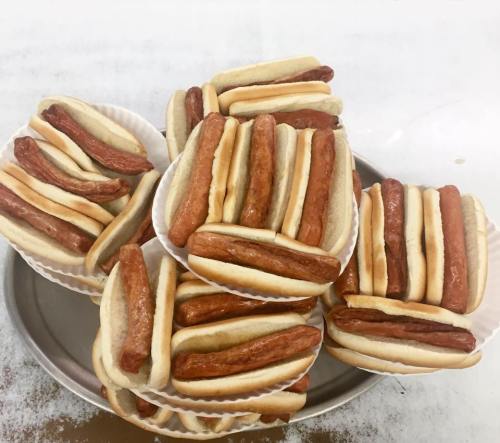 A tray of hot dogs in buns, stacked neatly in paper cups, ready to be served.