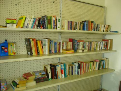 A bookshelf filled with various books arranged on multiple shelves in a well-lit room.