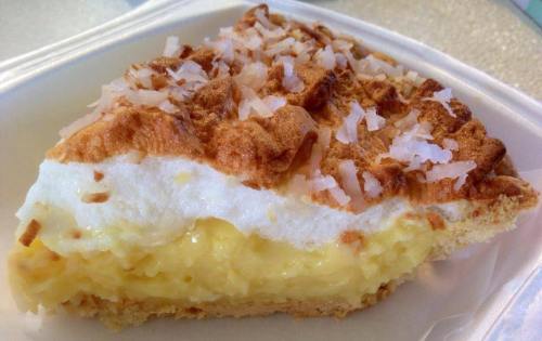 A slice of coconut cream pie with a golden crust and topped with shredded coconut.