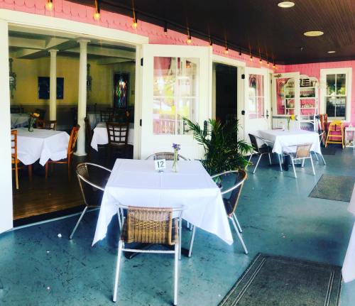 A bright restaurant interior with white tablecloths, chairs, and pink walls, featuring an inviting atmosphere.