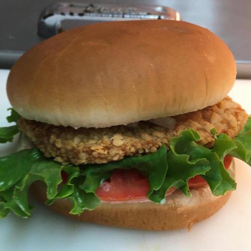 A crispy chicken sandwich with lettuce, tomato, and mayonnaise on a soft bun.