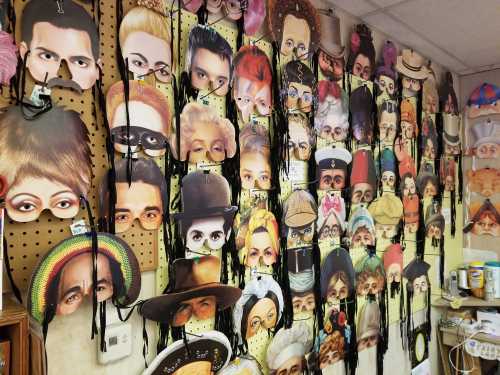 A wall covered with various face masks and costume accessories, featuring diverse faces and expressions.