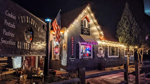 A cozy coffee shop at night, adorned with string lights and an American flag, featuring a welcoming atmosphere.
