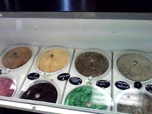 A display of various ice cream flavors in tubs, including vanilla, chocolate, mint chocolate chip, and cookie cream.