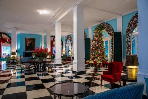 Elegant lobby decorated for Christmas, featuring a colorful tree, floral arrangements, and a black-and-white checkered floor.