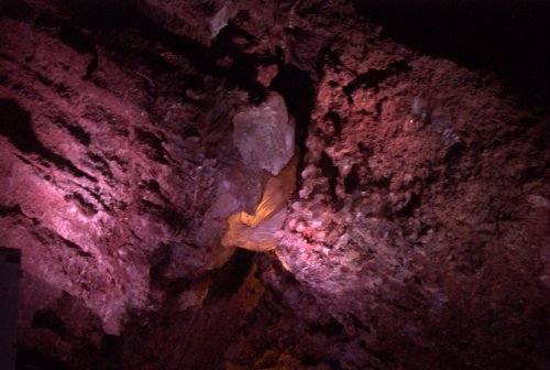 Colorful rock formations illuminated in a cave, showcasing textures and mineral deposits.