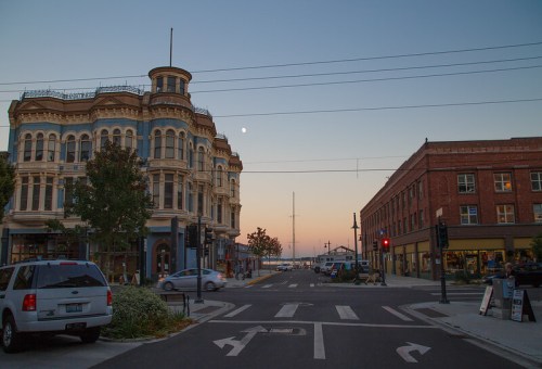 Historic buildings at sunset, with a clear sky and a hint of the moon, along a quiet street.