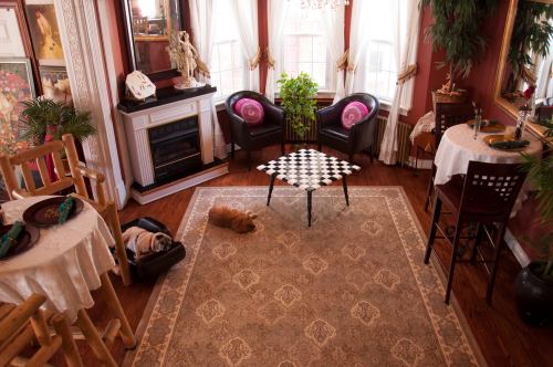 Cozy living room with a checkered table, two chairs, a dog resting, and large windows letting in natural light.