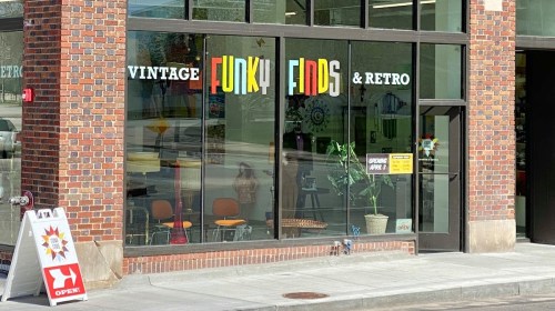 Storefront of "Vintage Funky Finds & Retro" with large colorful signage and an open sign outside.