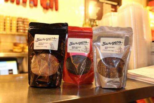Three bags of Sarge's snacks in black, red, and silver packaging displayed on a countertop.