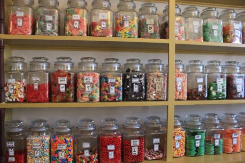 A colorful display of jars filled with various candies arranged on shelves.