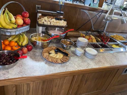 A buffet table featuring fruits, cookies, bread, and various dishes in bowls, with utensils for serving.