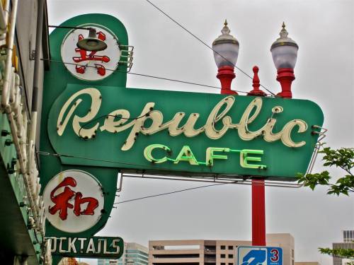 Vintage neon sign for Republic Café, featuring green and white lettering with decorative elements.