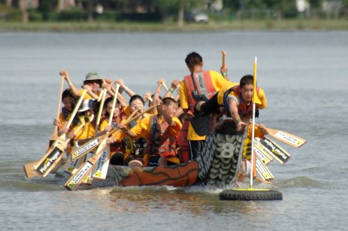A team of paddlers in a dragon boat races across a lake, showcasing teamwork and excitement.