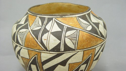 A decorative pottery jar featuring intricate geometric patterns in black, orange, and cream colors.