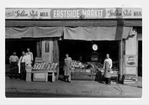 Black and white photo of Eastside Market with five men outside, surrounded by fresh produce and a sign for Golden State Milk.