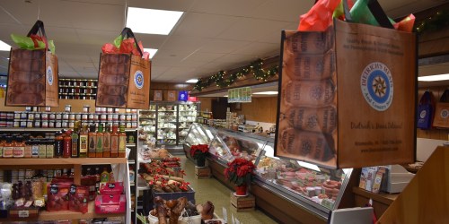 A cozy grocery store interior with festive decorations, showcasing hanging gift bags and a variety of food items.