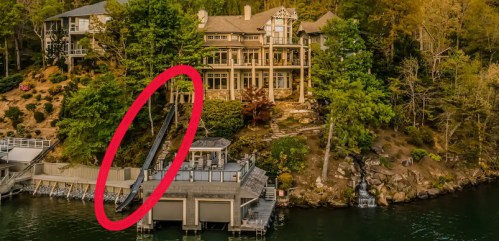 Aerial view of a large house on a lakeside, with a dock and surrounding trees. A red circle highlights a specific area.