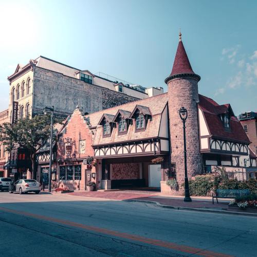 A charming building with a turret and sloped roofs, set against a clear blue sky in an urban area.