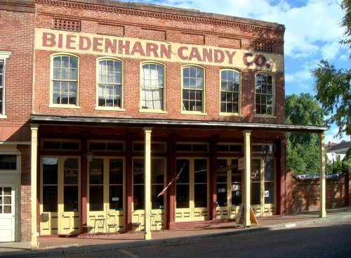 Historic brick building with "Biedenharn Candy Co." sign, featuring large windows and a welcoming entrance.