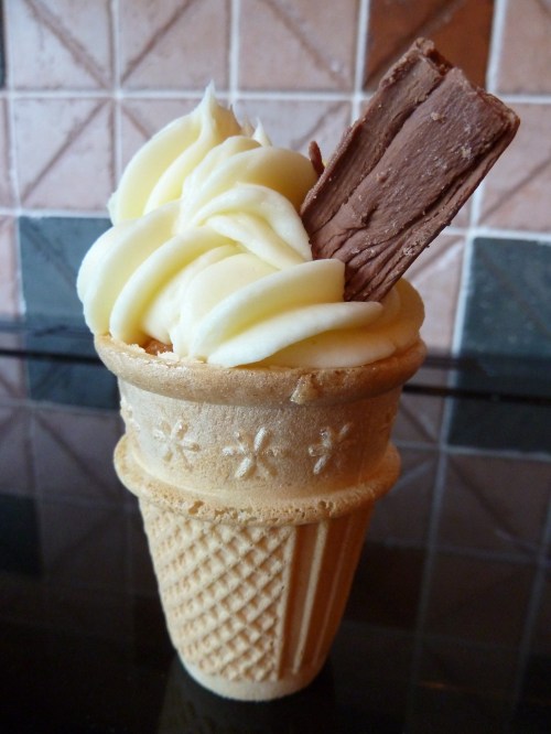 A delicious ice cream cone topped with creamy swirls and a chocolate wafer stick.
