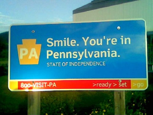 Blue sign welcoming visitors to Pennsylvania, stating "Smile. You're in Pennsylvania. STATE OF INDEPENDENCE."
