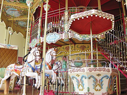 A colorful carousel featuring ornate horses and a decorative canopy, set in a vibrant amusement park.