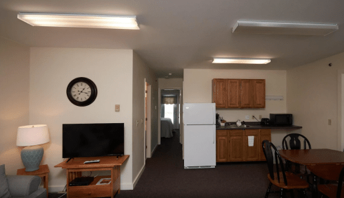 A cozy living space featuring a TV, dining table, kitchen area, and a clock on the wall.