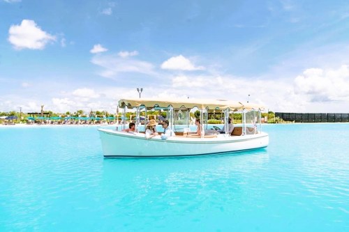 A white boat with passengers floats on bright turquoise water under a clear blue sky.