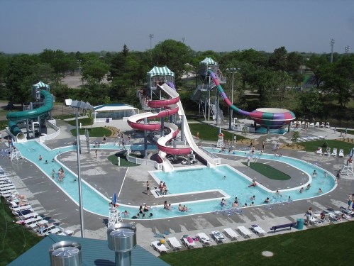 Aerial view of a water park featuring multiple slides, a lazy river, and a swimming pool with people enjoying the water.