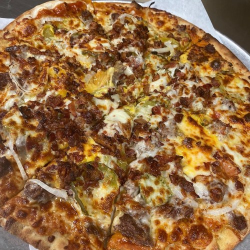 A close-up of a pizza topped with cheese, bacon, sausage, and green peppers on a golden crust.