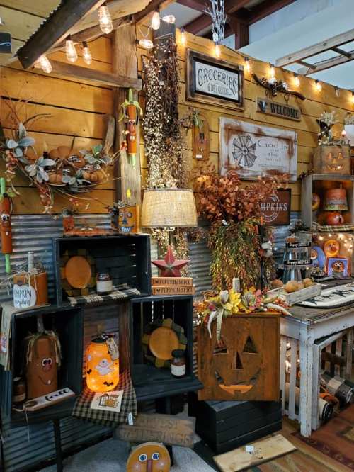 A cozy fall display featuring pumpkins, autumn decor, and warm lighting in a rustic setting.
