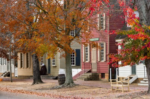 Historic houses with autumn foliage, featuring vibrant red and orange leaves, on a quiet street.