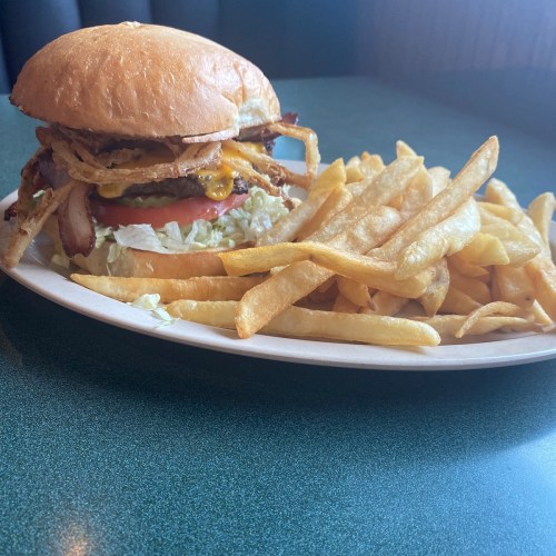 A hearty burger topped with bacon, cheese, and crispy onions, served with a side of golden French fries.