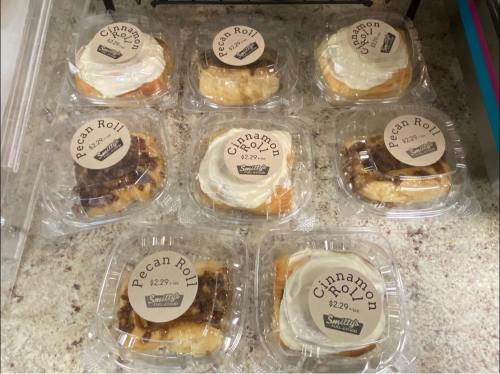A display of eight pastries in clear containers, labeled as Pecan Rolls and Cinnamon Rolls, priced at $2.29 each.