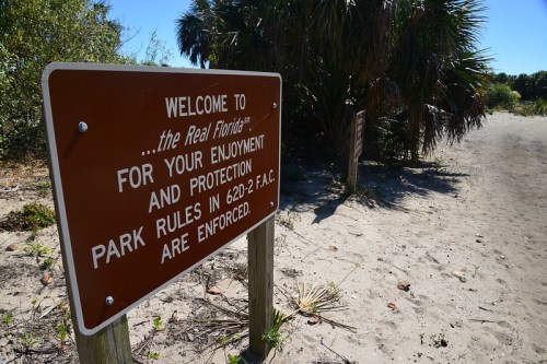 A brown sign reads "Welcome to the Real Florida" with park rules and regulations for visitor protection.