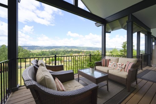 A cozy outdoor seating area with a view of rolling hills and blue skies, featuring a sofa and coffee table.