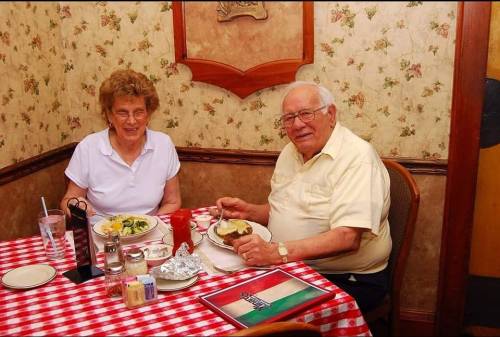 An elderly couple enjoys a meal together at a cozy restaurant with a checkered tablecloth.