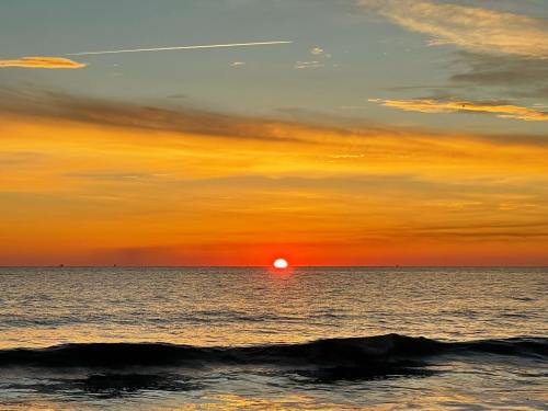 A vibrant sunset over the ocean, with warm orange and yellow hues reflecting on the water's surface.