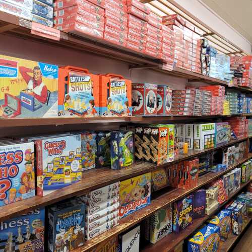 A colorful display of various board games and puzzles on wooden shelves in a store.