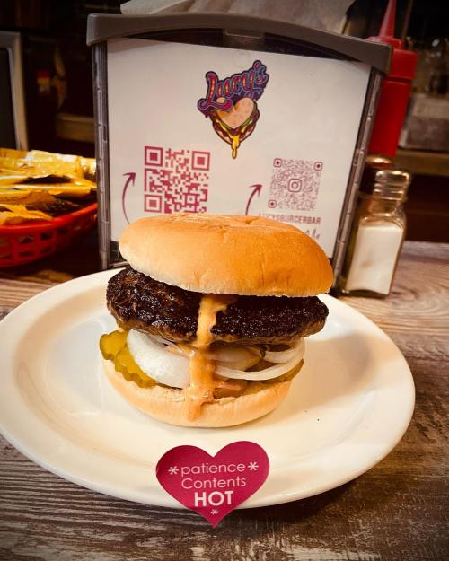 A juicy burger with melted cheese, pickles, and onions on a bun, served on a plate at a diner.