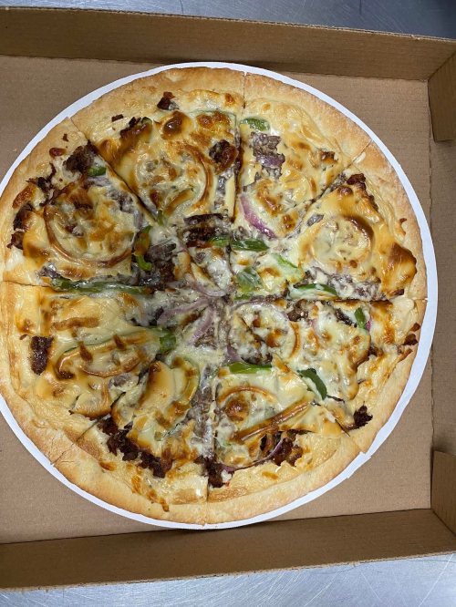 A pizza with a golden crust, topped with cheese, green peppers, and various meats, cut into slices in a pizza box.