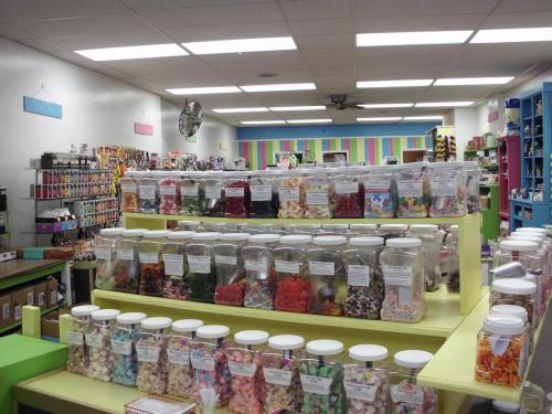A colorful candy store interior with jars of various candies displayed on shelves and a vibrant, cheerful atmosphere.