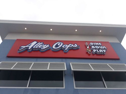 Sign for "Alley Oops" featuring the tagline "Dine, Bowl, Play" on a blue building.