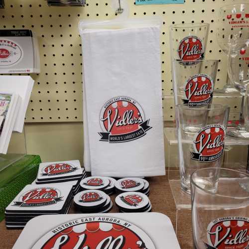 Display of merchandise from Vidler's, including towels, coasters, and glasses, featuring the store's logo.