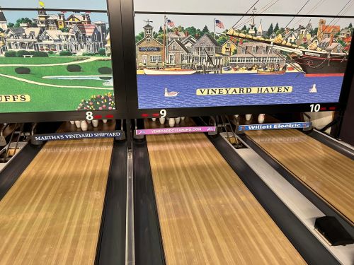 Bowling lanes with colorful murals of Vineyard Haven and Martha's Vineyard Shipyard in the background.