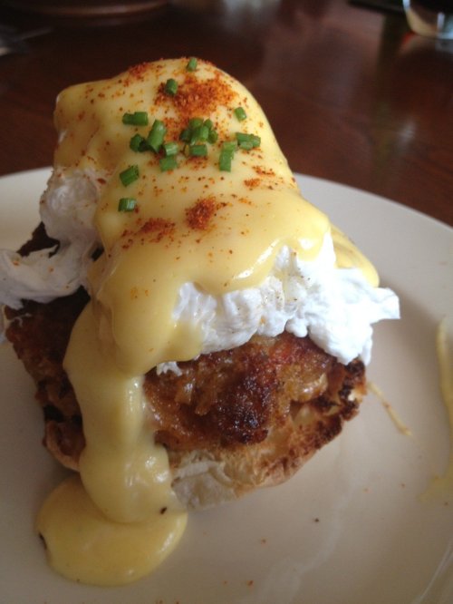 A toasted bun topped with a poached egg, creamy hollandaise sauce, and sprinkled with chives and paprika.