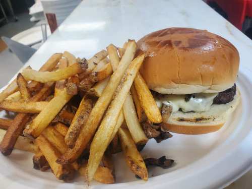 A plate with a cheeseburger and a generous serving of golden, crispy French fries.