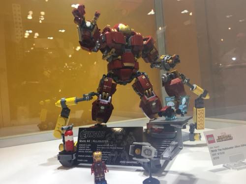 A detailed LEGO model of the Hulkbuster from Avengers, featuring Iron Man and a display stand.