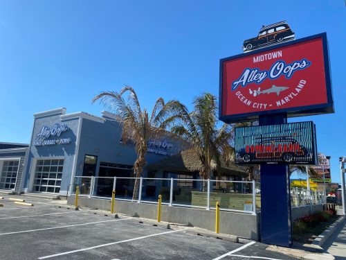Exterior of Alley Oops restaurant in Ocean City, Maryland, featuring palm trees and a bright sign against a clear blue sky.